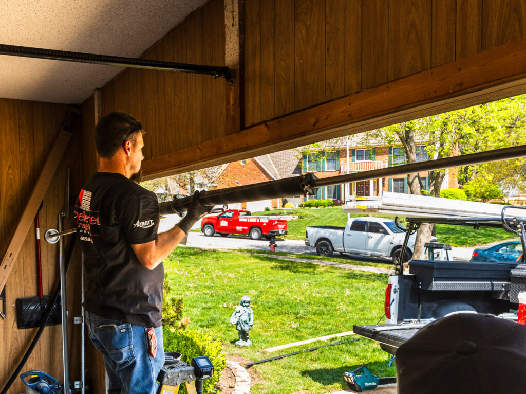 A repairman standing on a ladder, completing a garage door installation in Lenexa.