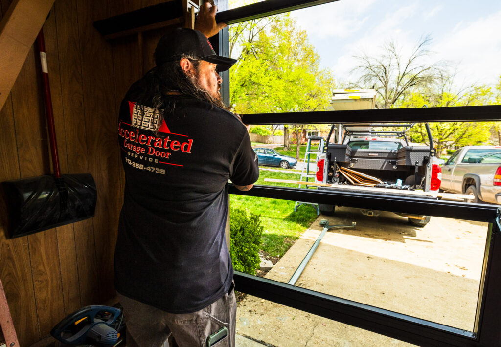 An AGDS technician carefully aligns new panels during a garage door service in Olathe.