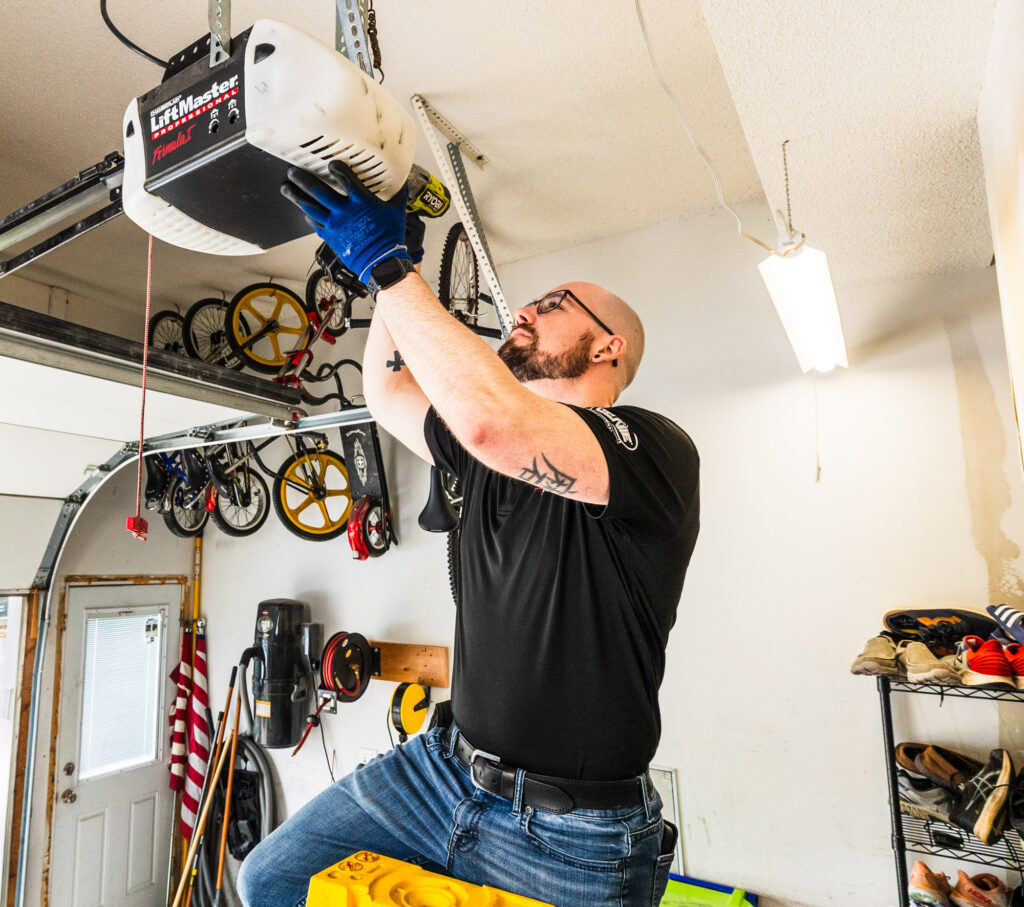 A team member from our garage door company in Overland Park working on a Lift Master opener inside a garage.