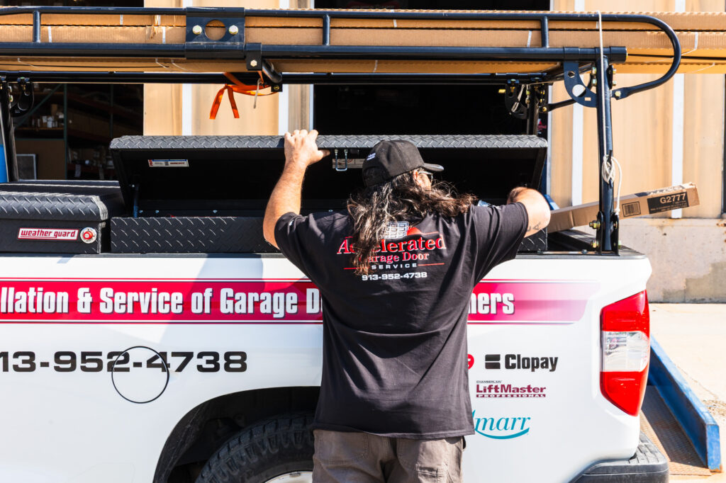 A technician for garage door repair service in Shawnee standing next to a truck.