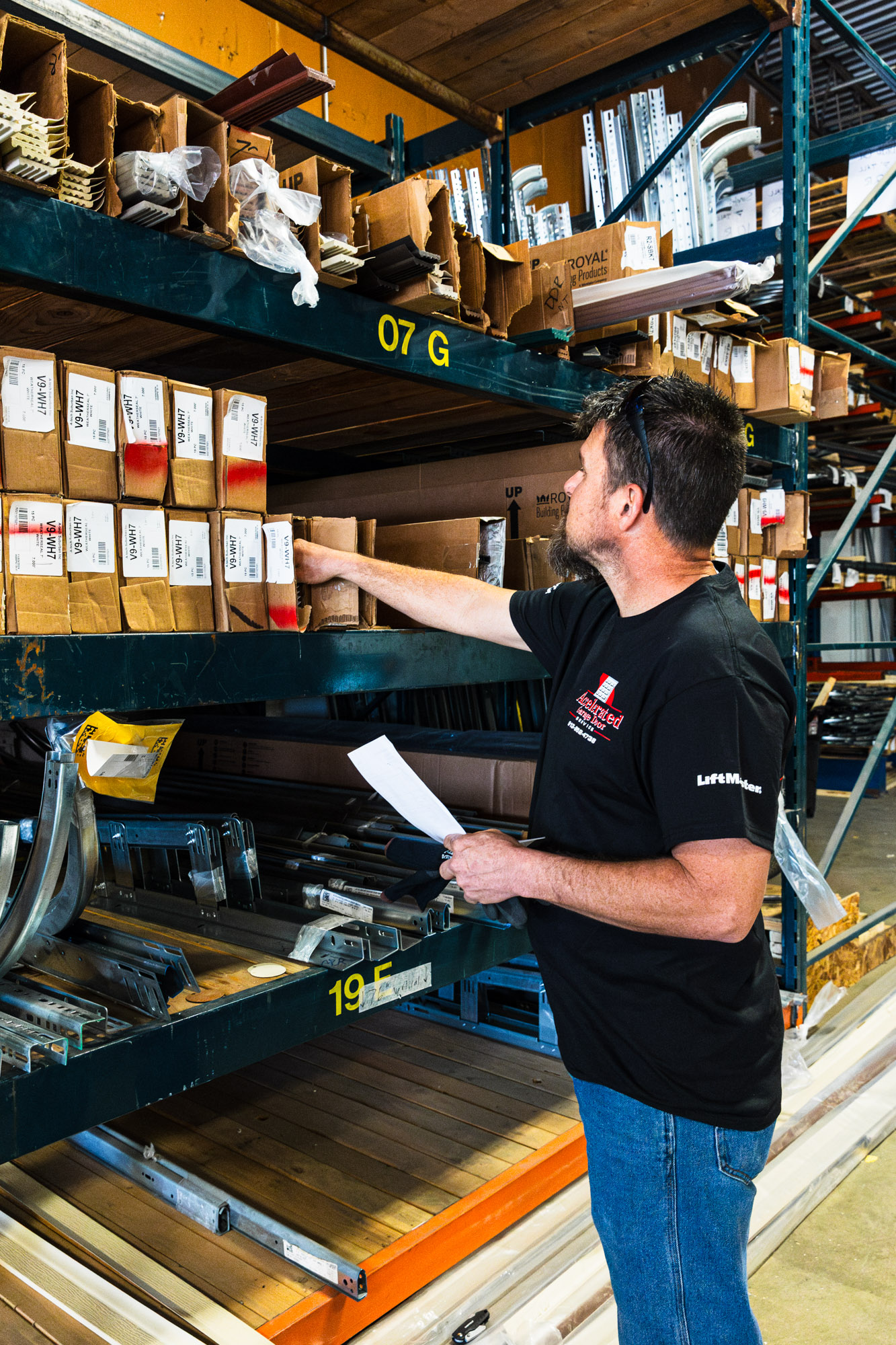 Garage door repairman grabbing items from a shelf to use for garage door installation.